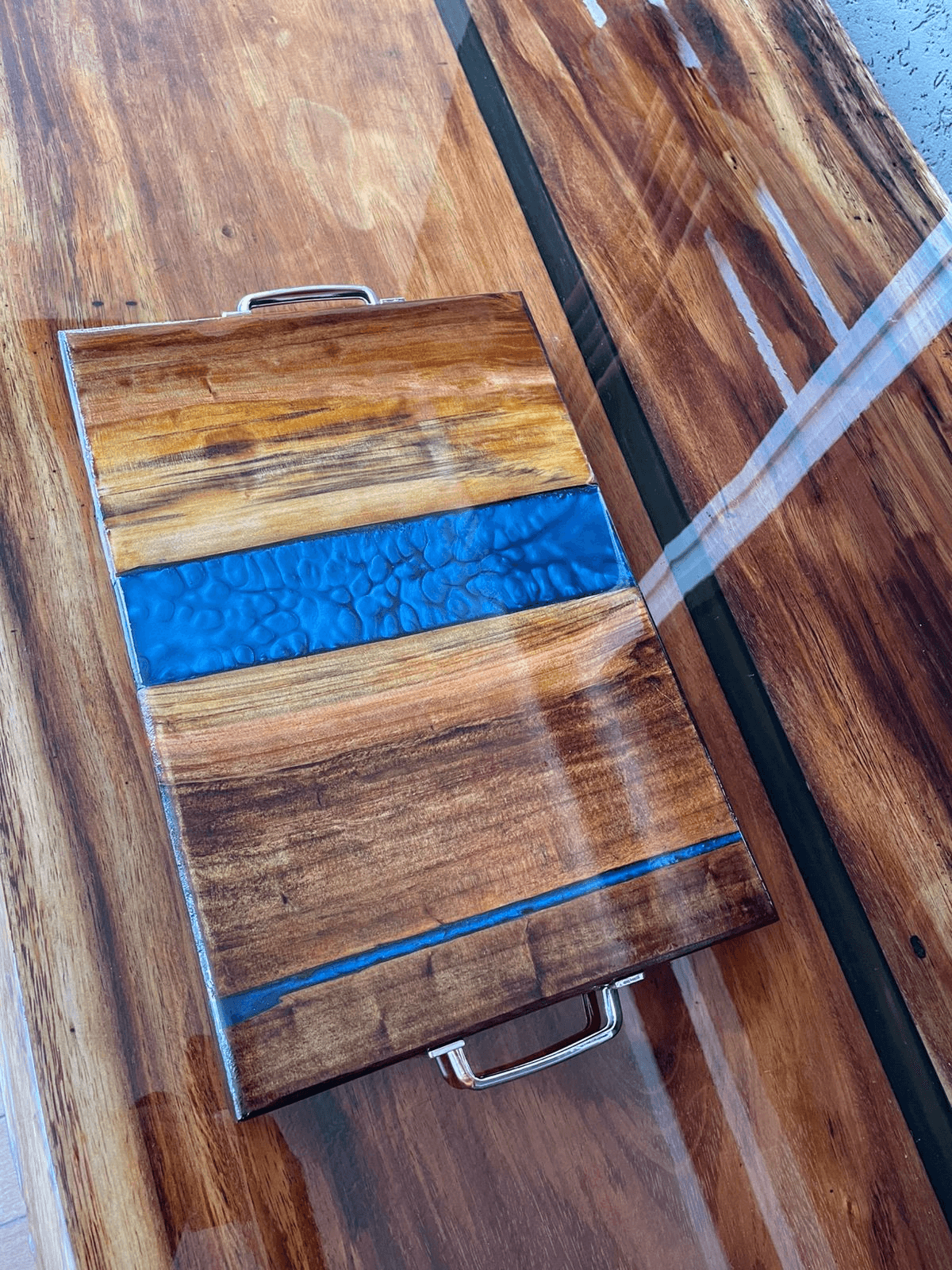 Bandeja artesanal em madeira com rio de resina azul e alcas em metal